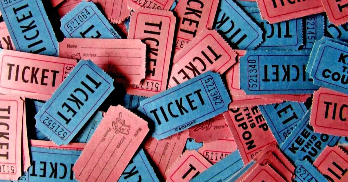 A close-up of a pile of red and blue raffle tickets. Each ticket has black text and a unique number combination.